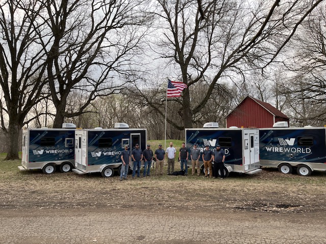 wire world crew standing in front of their work trailers